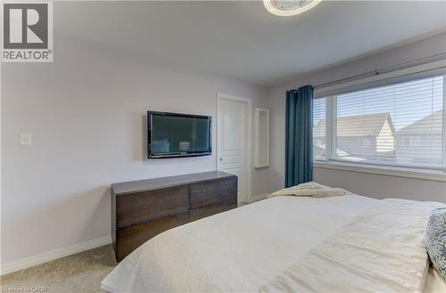 Carpeted flooring, window with blinds, wall-mounted television, built-in shelving, and a flush mount ceiling light fixture - 428 Freure Drive, Cambridge, ON 