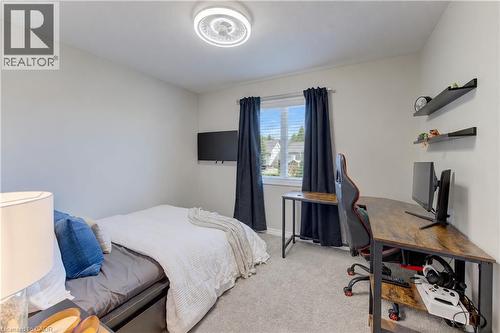 Recessed lighting fixture, light gray carpeting, window with blinds, wall-mounted television, and wood-finish corner desk - 428 Freure Drive, Cambridge, ON 