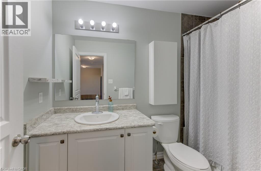 Vanity with an integrated sink and stone-finish countertop, wall-mounted mirror, overhead four-bulb vanity lighting, and wall-mounted storage cabinet - 428 Freure Drive, Cambridge, ON