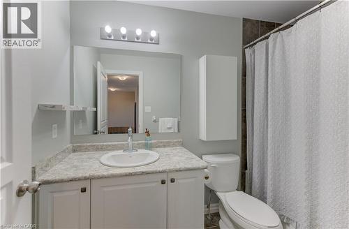 Vanity with an integrated sink and stone-finish countertop, wall-mounted mirror, overhead four-bulb vanity lighting, and wall-mounted storage cabinet - 428 Freure Drive, Cambridge, ON 