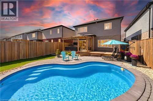 Backyard oasis featuring an in-ground swimming pool, wood-finish deck, pergola, and privacy fencing - 428 Freure Drive, Cambridge, ON 