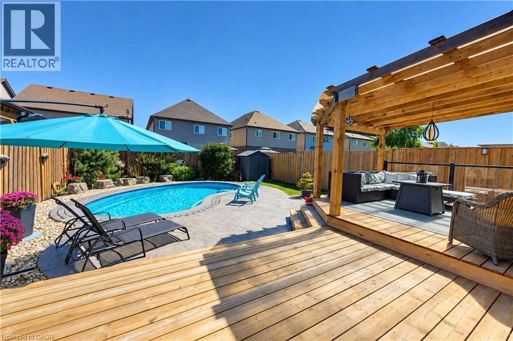 Wood-plank deck with a pergola, stone patio, and an in-ground swimming pool - 428 Freure Drive, Cambridge, ON