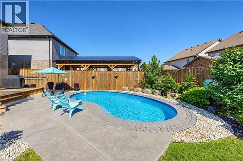 Backyard oasis featuring an in-ground pool with paver coping, concrete patio, wood deck, and a privacy fence - 428 Freure Drive, Cambridge, ON 