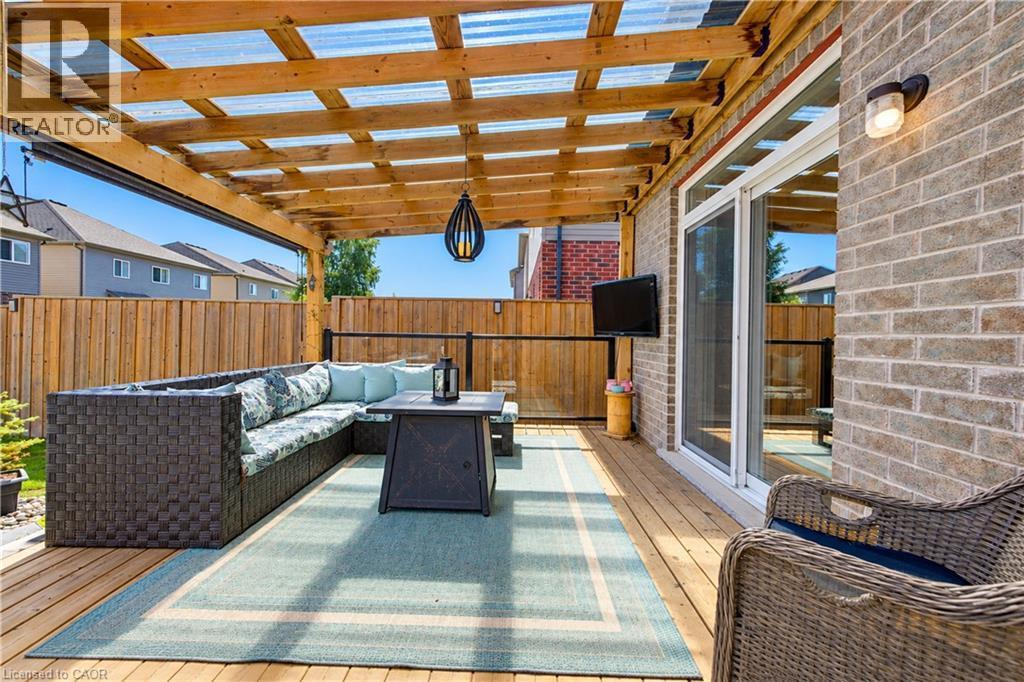 Covered outdoor deck with a wood pergola, clear panel roofing, and a privacy fence - 428 Freure Drive, Cambridge, ON