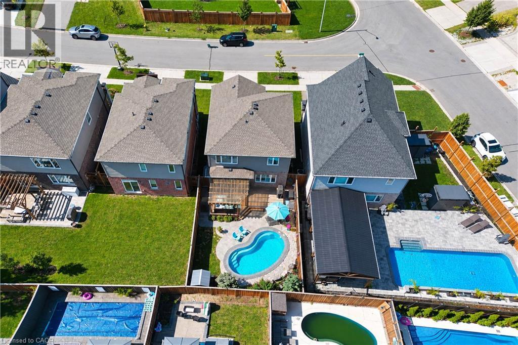Rear exterior with a private swimming pool, paved patio, wood deck, and fenced yard - 428 Freure Drive, Cambridge, ON