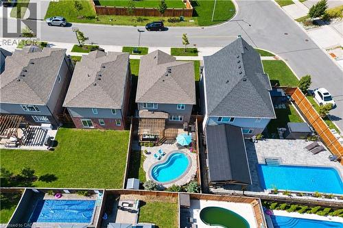 Rear exterior with a private swimming pool, paved patio, wood deck, and fenced yard - 428 Freure Drive, Cambridge, ON 