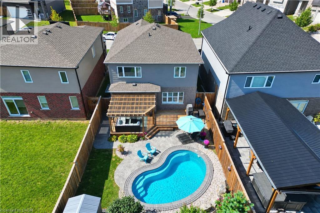 Rear exterior featuring a kidney-shaped swimming pool, paved patio, wood deck with a pergola. - 428 Freure Drive, Cambridge, ON
