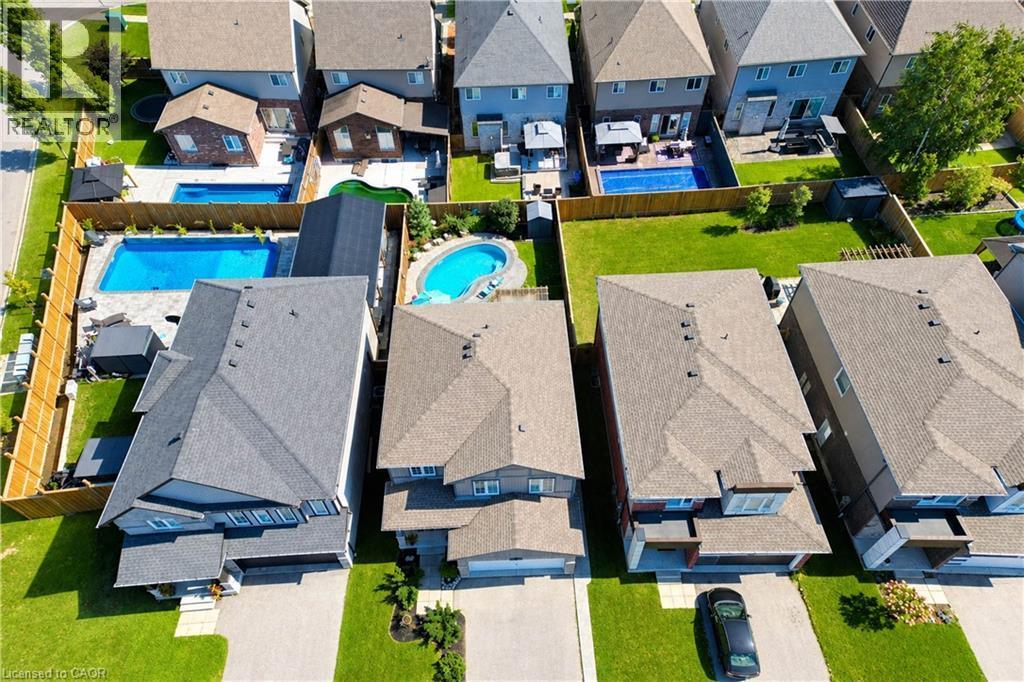 Expansive fenced backyard featuring a rectangular swimming pool and patio area - 428 Freure Drive, Cambridge, ON