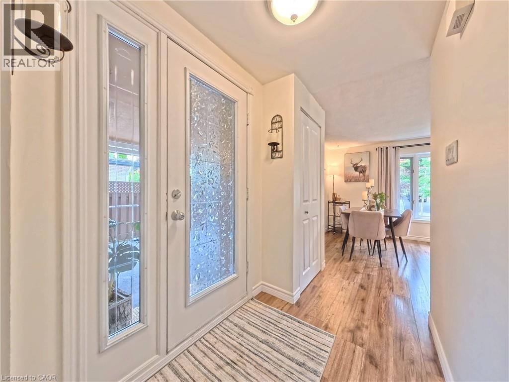 Entryway featuring a double door with decorative glass, wood-finish flooring, and a built-in coat closet - 380 Grangewood Drive, Waterloo, ON