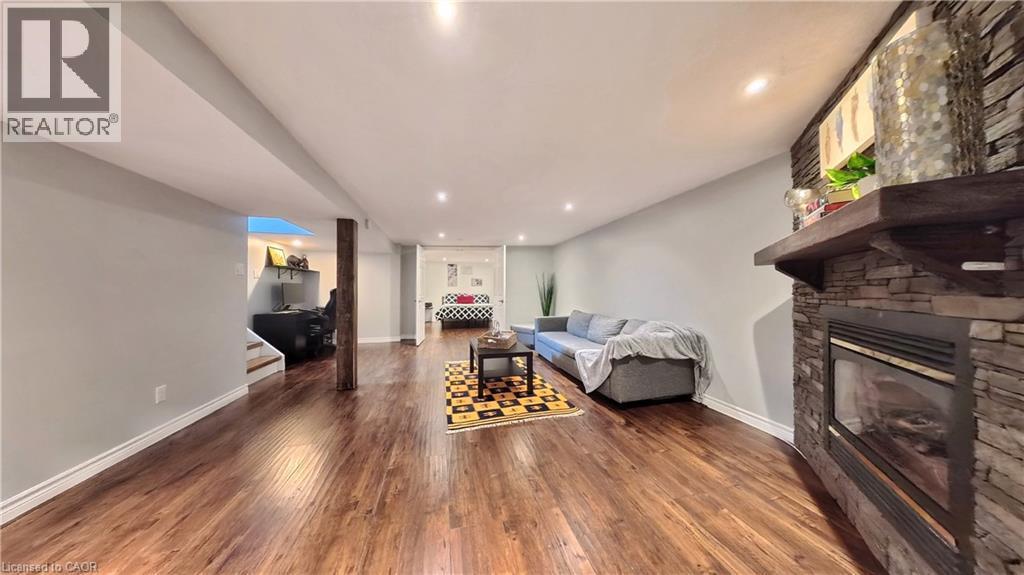 Wood-finish flooring throughout, recessed lighting, and a stone-clad fireplace with a wood mantel - 380 Grangewood Drive, Waterloo, ON