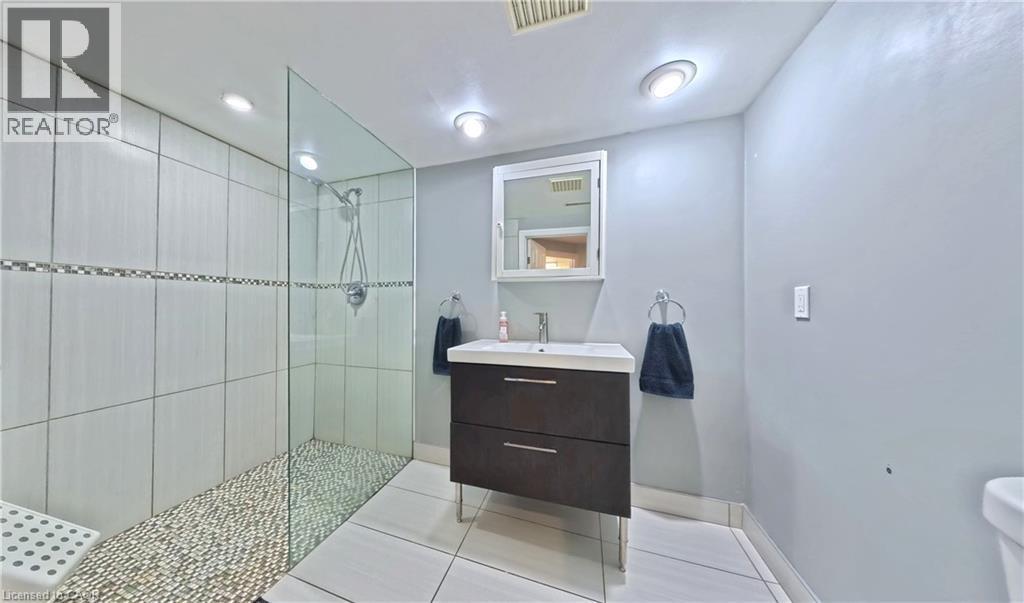 Walk-in shower with glass enclosure, pebble flooring, and white wall tile with decorative accent - 380 Grangewood Drive, Waterloo, ON