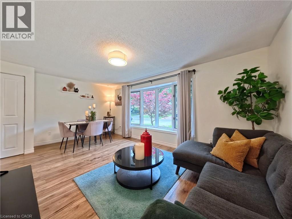 Wood-finish flooring throughout, featuring a curved bay window, a ceiling-mounted light fixture, and a built-in wall shelf - 380 Grangewood Drive, Waterloo, ON