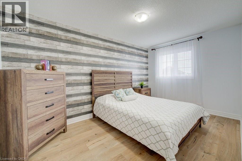 Light wood-finish flooring complements a feature wall with horizontal wood-look paneling - 300 Watervale Crescent, Kitchener, ON