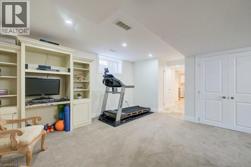 Lower-level room featuring built-in cabinetry with shelving, recessed lighting, a window, and a door leading to an adjacent area with tile flooring - 300 Watervale Crescent, Kitchener, ON