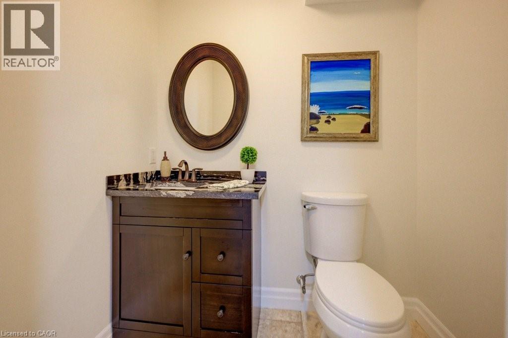 Vanity featuring a dark wood-finish cabinet with storage, a dark countertop, and a circular framed mirror - 300 Watervale Crescent, Kitchener, ON