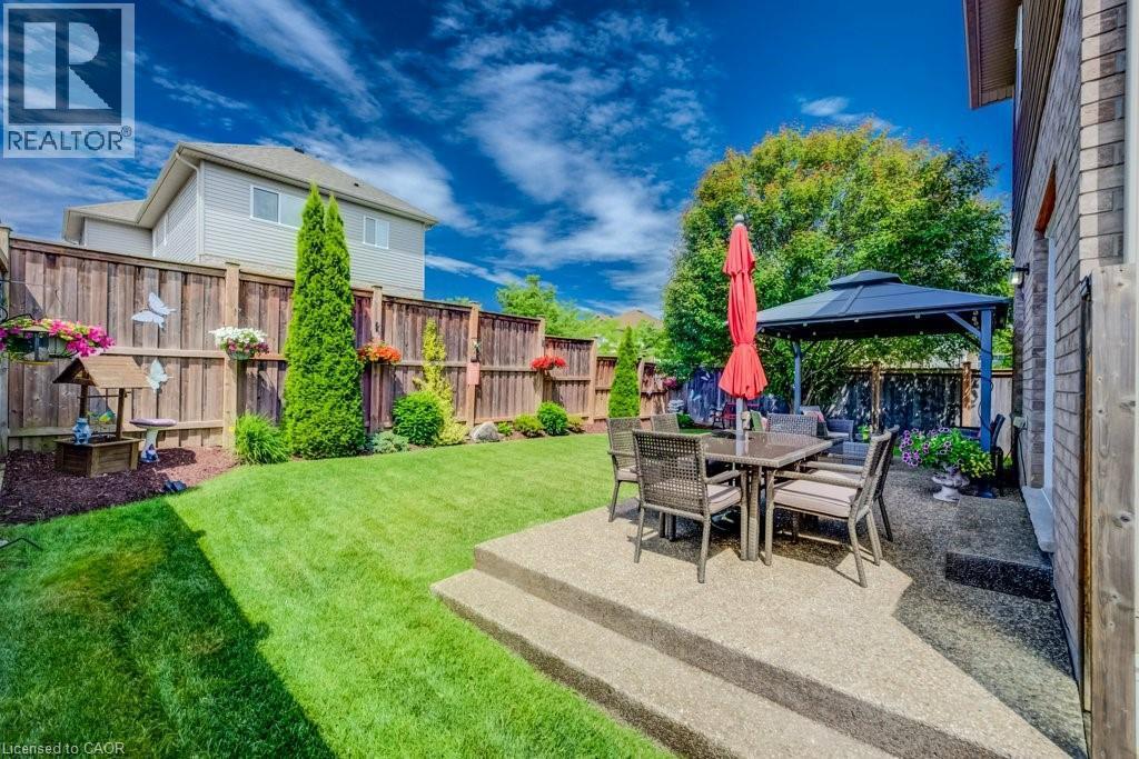 Expansive backyard featuring a tiered concrete patio, a dark-framed gazebo, and a manicured lawn - 300 Watervale Crescent, Kitchener, ON
