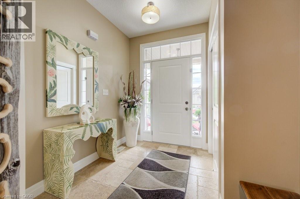 Entryway featuring a white paneled door with sidelights and transom window, light-toned stone-finish flooring, and a flush-mount ceiling light fixture - 300 Watervale Crescent, Kitchener, ON