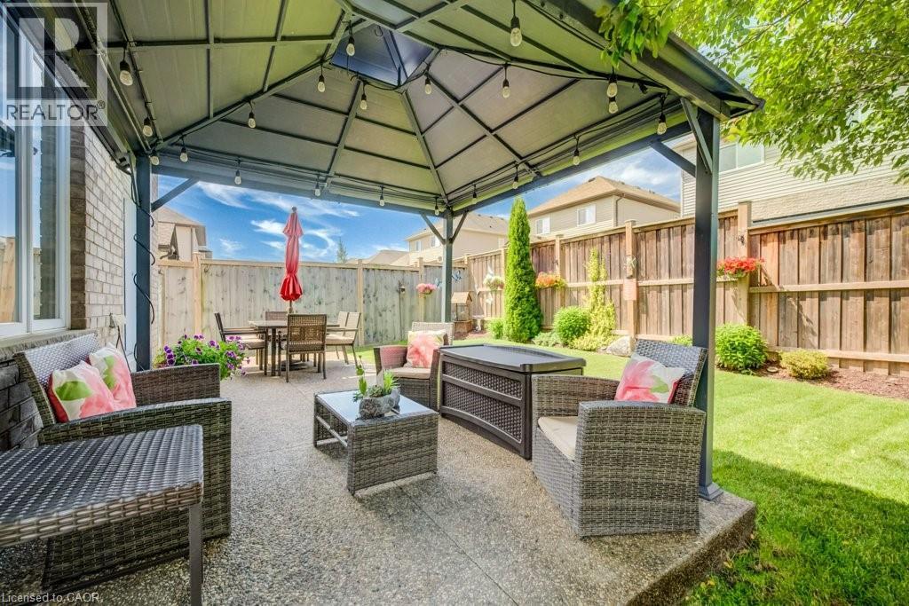Expansive patio featuring a permanent gazebo structure, string lighting, exposed aggregate concrete, and a manicured lawn - 300 Watervale Crescent, Kitchener, ON