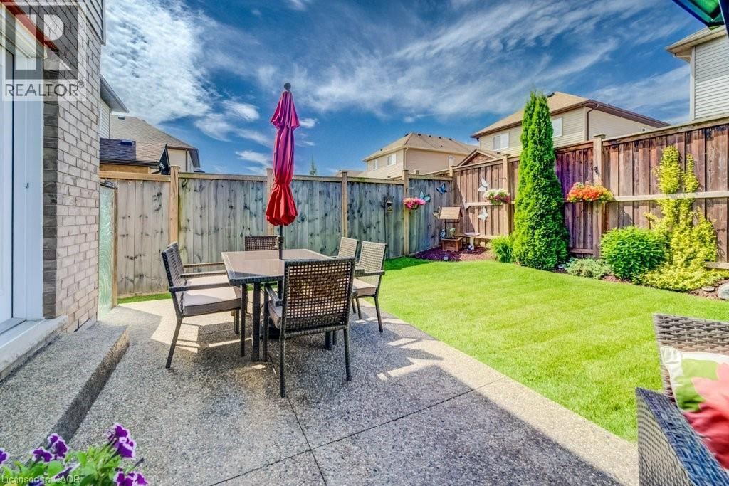 Private backyard featuring a concrete patio, wood fencing, and a manicured lawn - 300 Watervale Crescent, Kitchener, ON