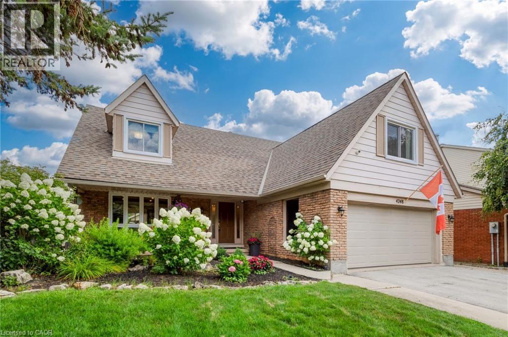 Brick and siding exterior featuring a prominent garage, dormer window, and mature landscaping - 4248 Dunvegan Road, Burlington, ON