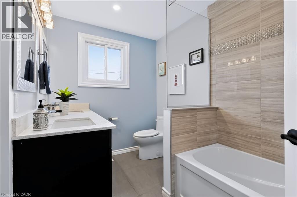 Modern bathroom featuring a sleek black vanity with white quartz countertop and integrated sink, soft-close cabinetry with ample storage, polished chrome fixtures, and a spa-like walk-in shower with w - 4248 Dunvegan Road, Burlington, ON
