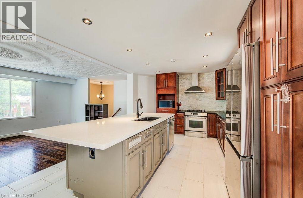 Spacious kitchen featuring a large central island, stainless steel appliances, wood cabinetry, and recessed lighting - 109 White Oak Place, Waterloo, ON - Indoor Photo Showing Kitchen With Double Sink With Upgraded Kitchen