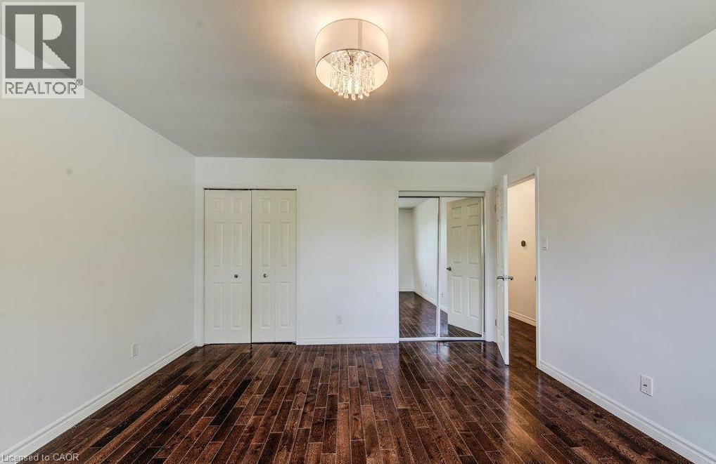 Dark wood-finish flooring, bi-fold closet doors, and a ceiling light. - 109 White Oak Place, Waterloo, ON - Indoor Photo Showing Other Room