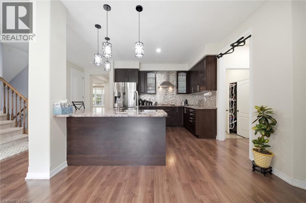 Kitchen featuring dark wood cabinetry, stainless steel appliances, and a mosaic tile backsplash - 57 Cheevers Road, Brantford, ON - Indoor Photo Showing Kitchen With Upgraded Kitchen