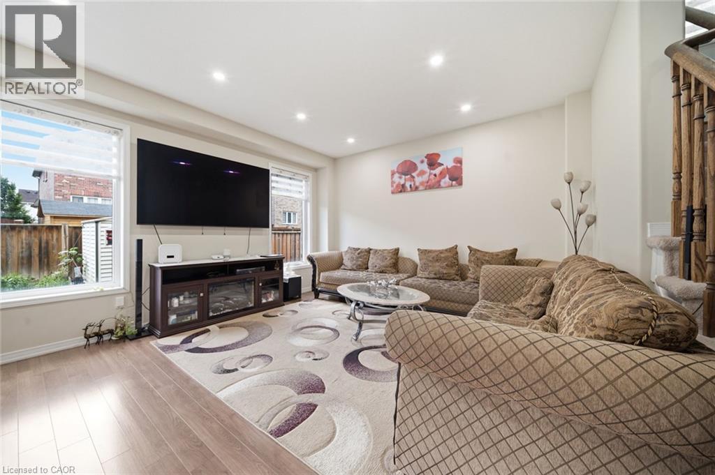Recessed ceiling lighting, wood-finish flooring, white wall paint, white window frames, and wood staircase railing - 57 Cheevers Road, Brantford, ON - Indoor Photo Showing Living Room