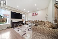 Recessed ceiling lighting, wood-finish flooring, white wall paint, white window frames, and wood staircase railing - 