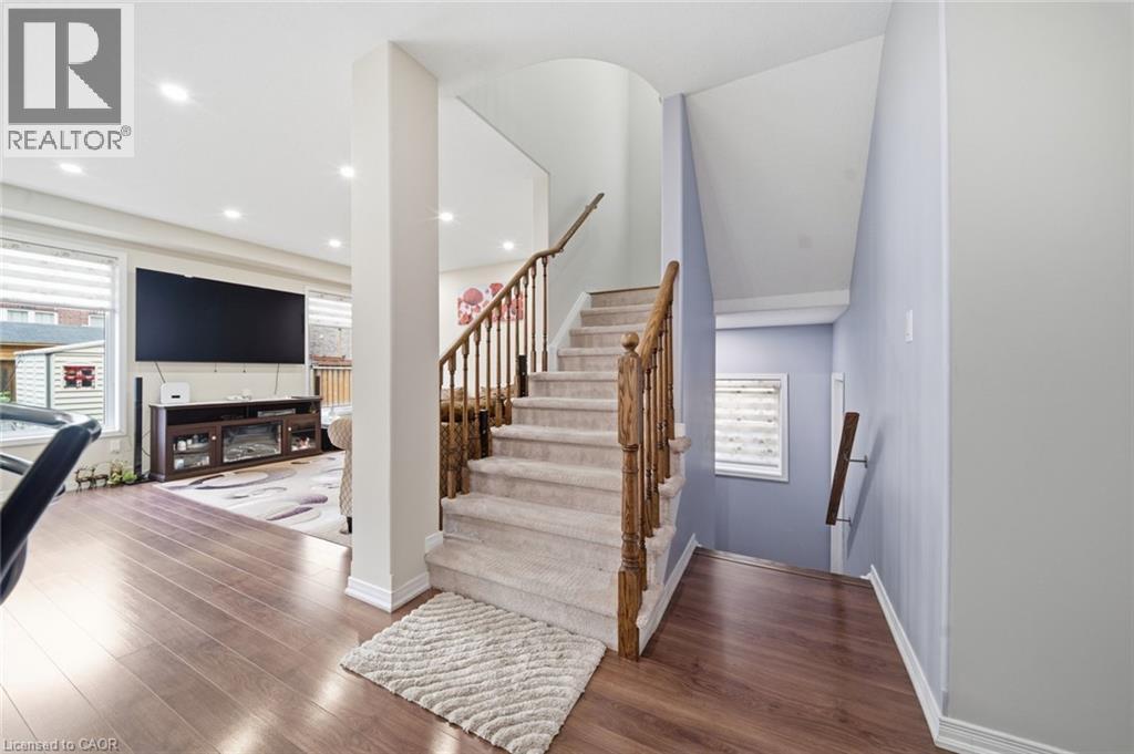Wood-finish flooring throughout, recessed lighting, and a carpeted staircase with wood banister - 57 Cheevers Road, Brantford, ON - Indoor Photo Showing Other Room