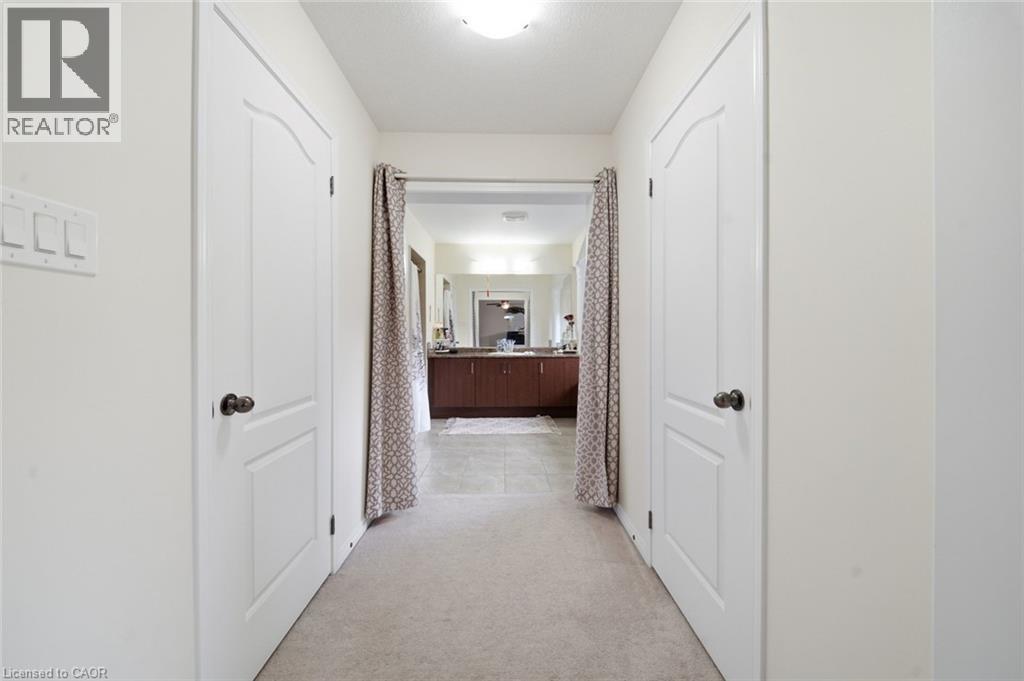 Carpeted hallway with two panel doors and an overhead light fixture - 57 Cheevers Road, Brantford, ON - Indoor Photo Showing Other Room