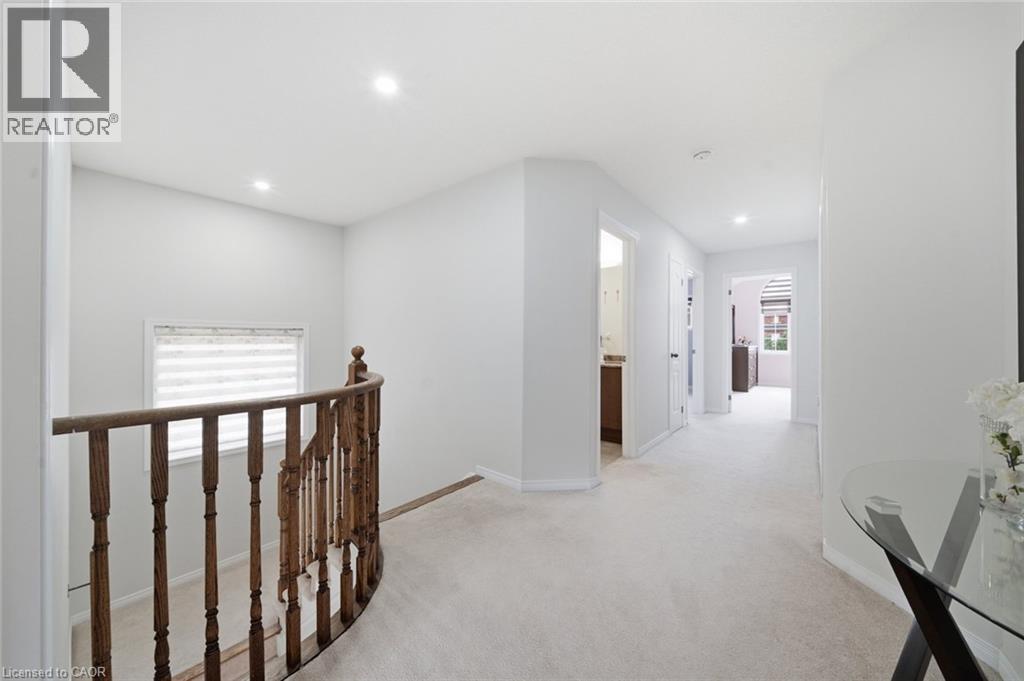 Curved wood-finish railing, recessed ceiling lighting, light-toned carpeting, and multiple doorways - 57 Cheevers Road, Brantford, ON - Indoor Photo Showing Other Room