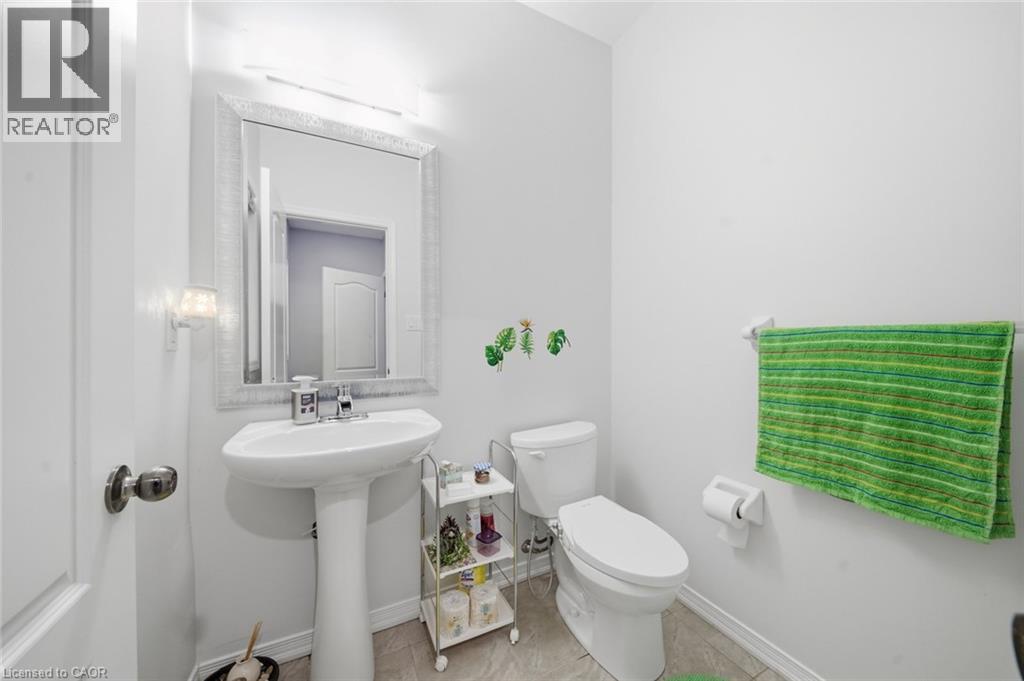 Pedestal sink with chrome faucet, framed mirror, wall-mounted light fixture, and tile flooring - 57 Cheevers Road, Brantford, ON - Indoor Photo Showing Bathroom