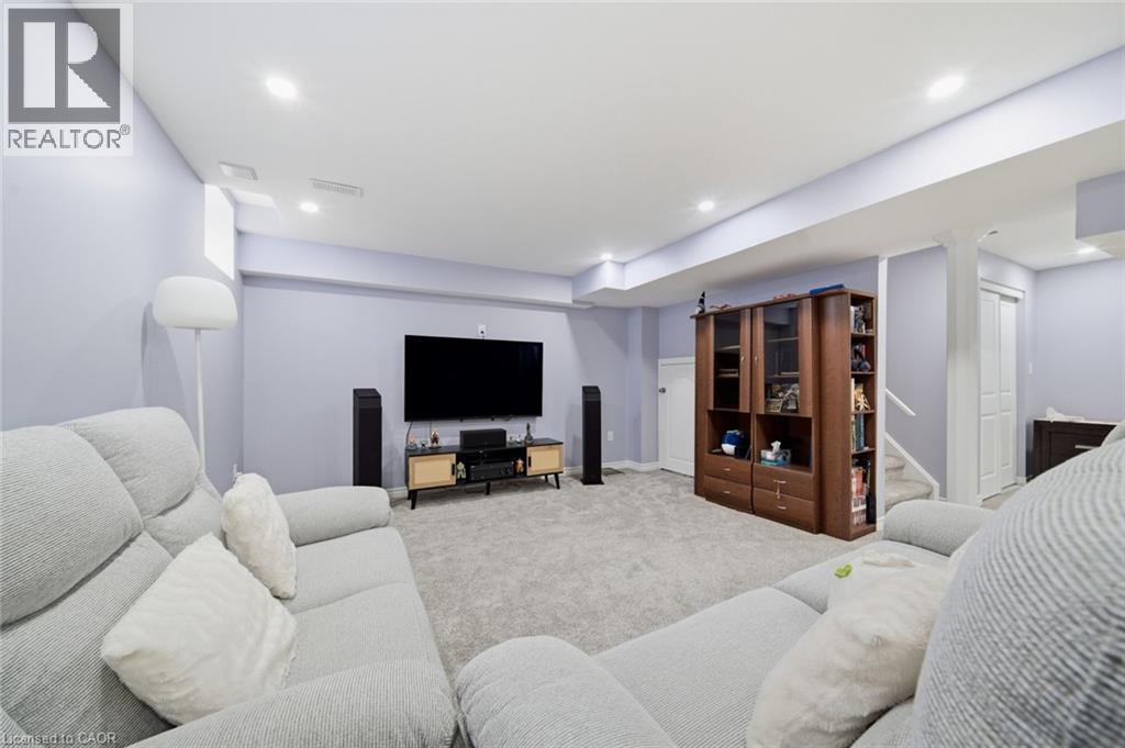 Recessed ceiling lighting, light gray wall paint, built-in shelving unit, carpet flooring, and a white staircase with a contrasting handrail - 57 Cheevers Road, Brantford, ON - Indoor