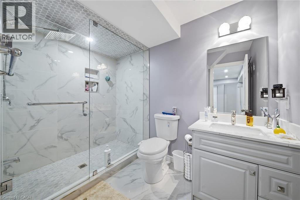 Walk-in shower with clear glass enclosure, rainfall showerhead, and recessed shelf niches - 57 Cheevers Road, Brantford, ON - Indoor Photo Showing Bathroom