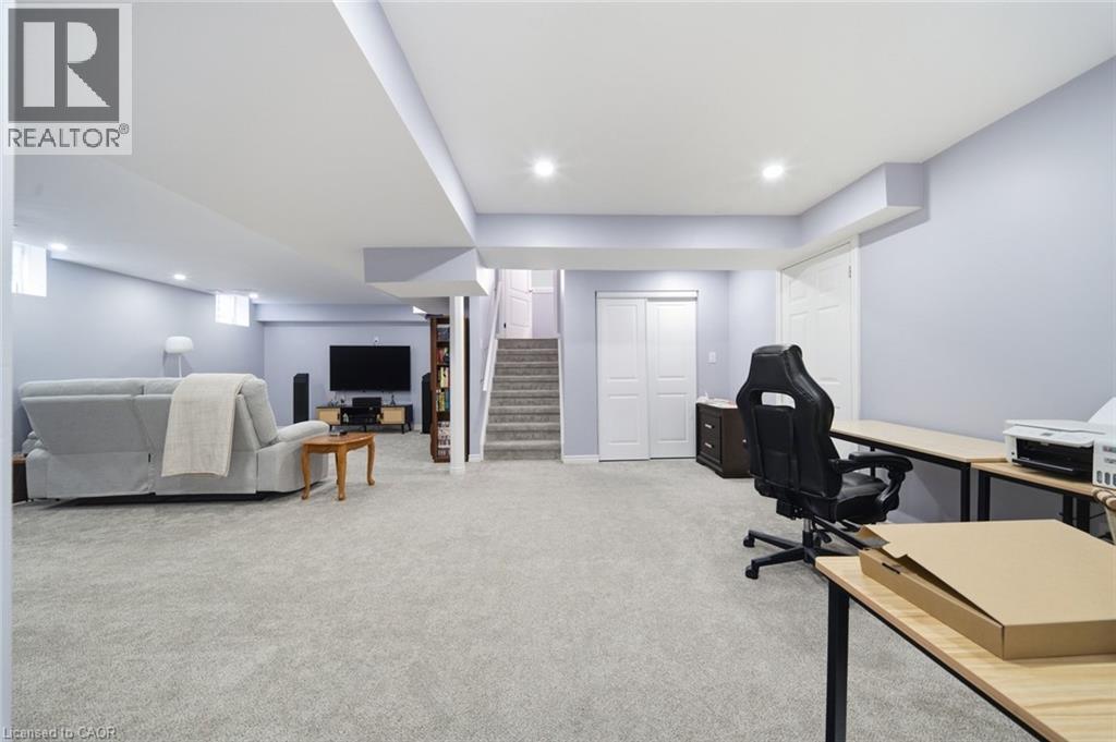 Expansive carpeted area with recessed lighting, offering a versatile space with a staircase, bi-fold closet doors, and additional storage - 57 Cheevers Road, Brantford, ON - Indoor