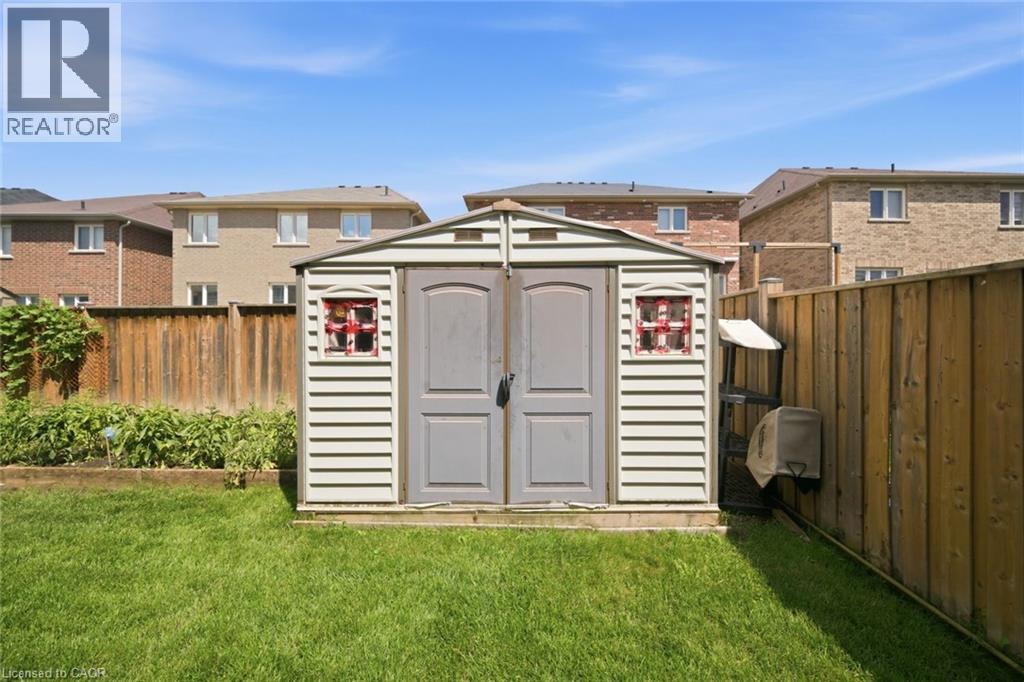 Spacious backyard featuring a storage shed with dual doors, a manicured lawn, and wood fencing - 57 Cheevers Road, Brantford, ON - Outdoor