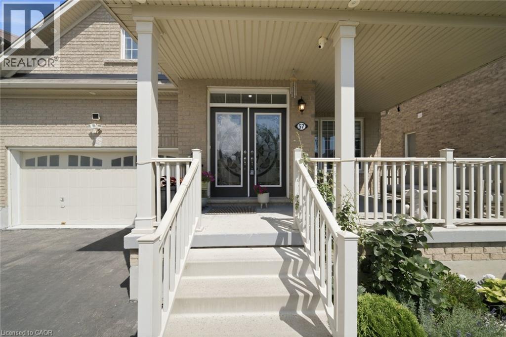 Covered porch with white railings and columns, featuring a double door entry with decorative glass, light brick exterior, and an attached garage - 57 Cheevers Road, Brantford, ON - Outdoor