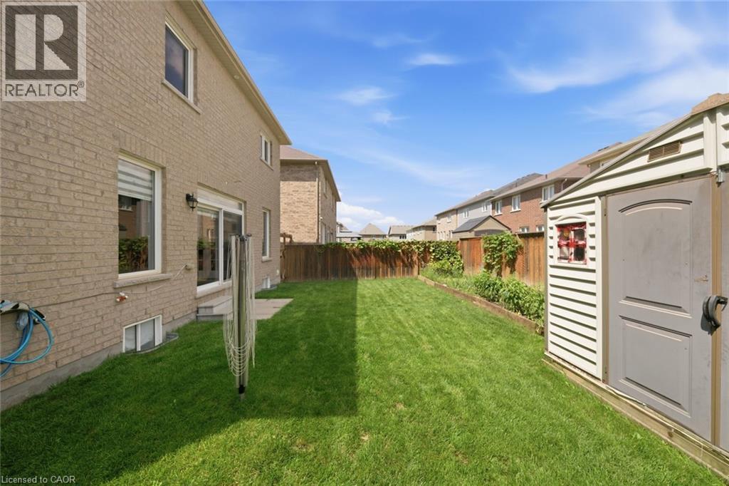 Expansive backyard featuring a manicured lawn, full fencing, and a storage shed - 57 Cheevers Road, Brantford, ON - Outdoor With Exterior