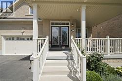 Covered porch with white railings and columns, featuring a double door entry with decorative glass, light brick exterior, and an attached garage - 