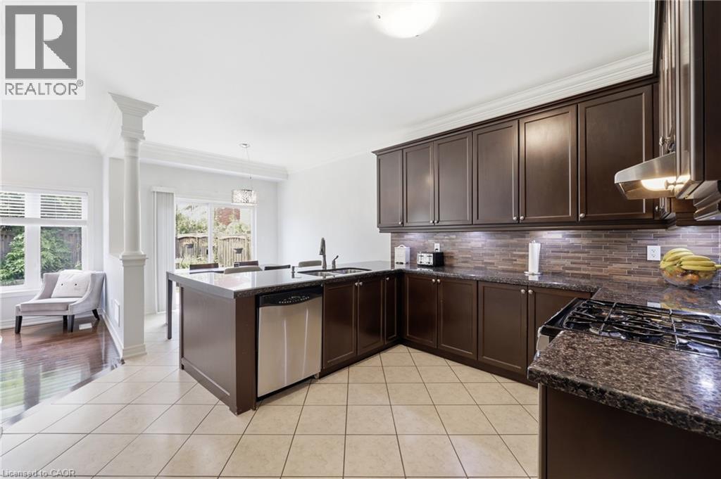 Kitchen featuring dark wood cabinetry, a gas range with a stainless steel hood, an integrated dishwasher, and a large central island - 738 Fourth Line, Milton, ON - Indoor Photo Showing Kitchen