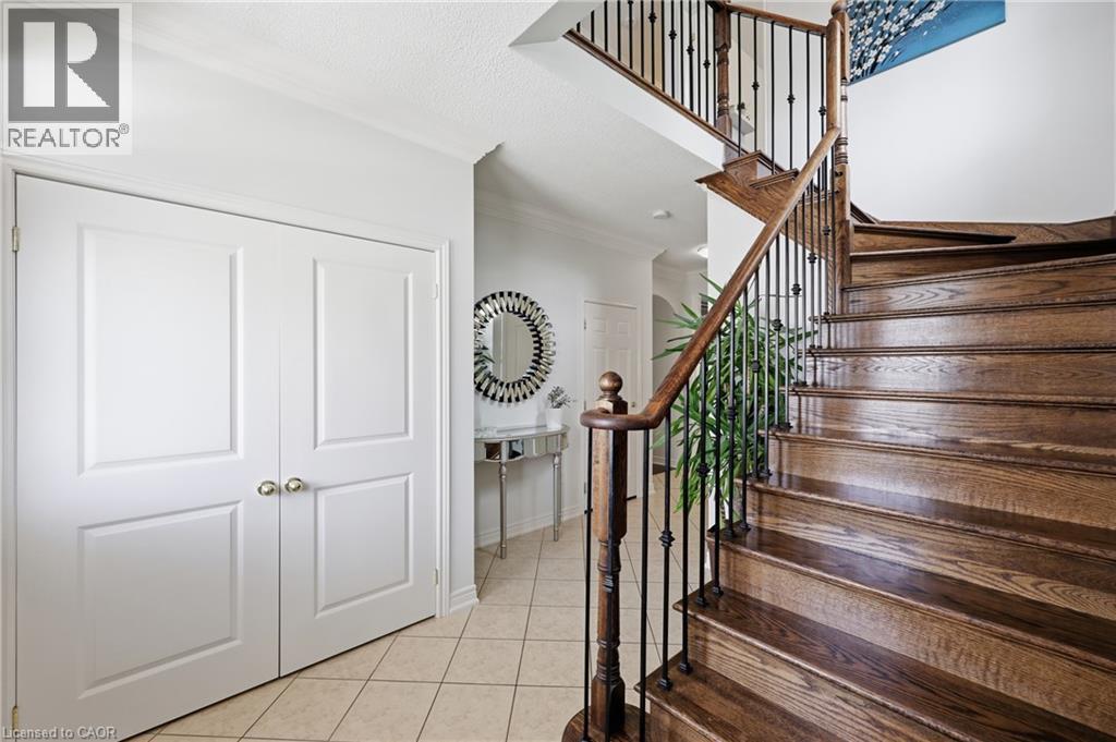 Curved hardwood staircase with wrought iron balusters, paneled double doors, and tile flooring - 738 Fourth Line, Milton, ON - Indoor Photo Showing Other Room