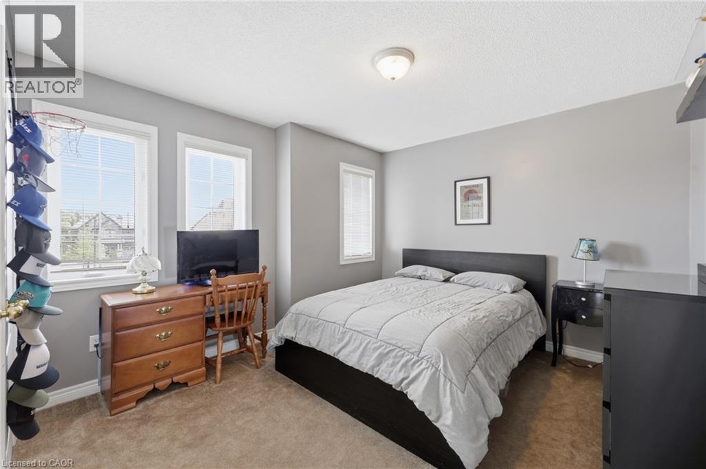 Light gray wall paint, two large windows with blinds, brown carpet flooring, and a ceiling-mounted light fixture - 738 Fourth Line, Milton, ON - Indoor Photo Showing Bedroom