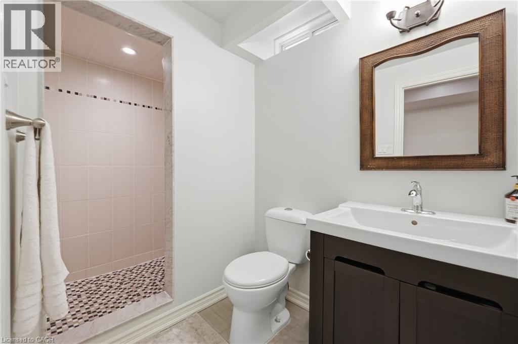 Shower stall with tiled walls and pebble-finish floor, wood-finish vanity with integrated sink, and wall-mounted mirror - 738 Fourth Line, Milton, ON - Indoor Photo Showing Bathroom