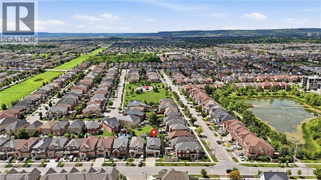Expansive aerial view of a residential development featuring numerous individual properties, a central green space, and a pond - 738 Fourth Line, Milton, ON - Outdoor With View