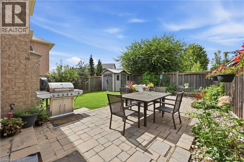 Paver patio with a dining area, manicured lawn, and wooden privacy fencing - 738 Fourth Line, Milton, ON - Outdoor
