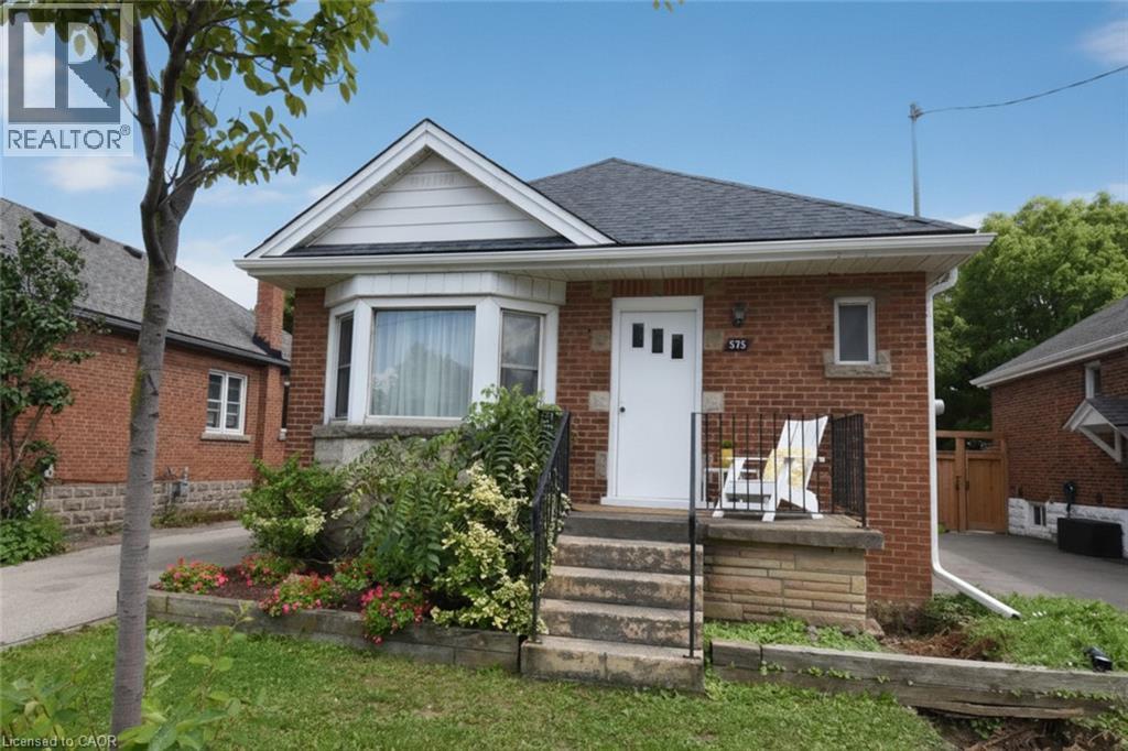 Brick exterior with a dark shingle roof, front bay window, and a white entry door - 575 Upper Wentworth Street, Hamilton, ON - Outdoor