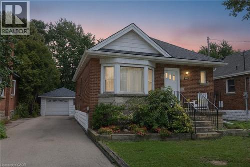 Brick exterior with a peaked roofline, front bay window, dedicated driveway, and a detached garage - 575 Upper Wentworth Street, Hamilton, ON - Outdoor