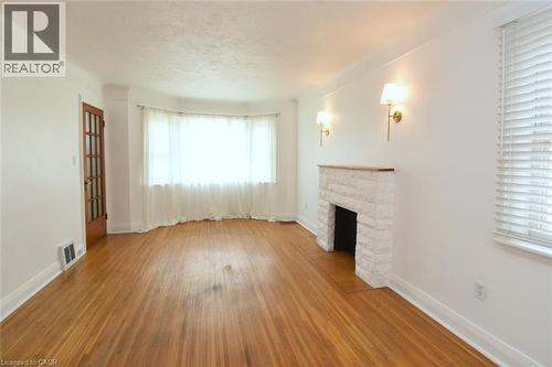 Wood-finish flooring, bay window, stone-clad fireplace with mantel, and sconce lighting - 575 Upper Wentworth Street, Hamilton, ON - Indoor With Fireplace